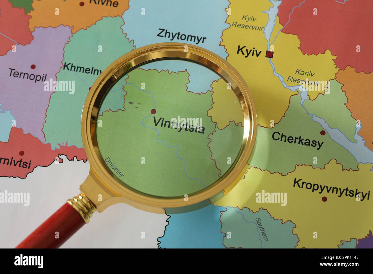 Golden magnifying glass above Vinnytsia region on map of Ukraine, closeup Stock Photo