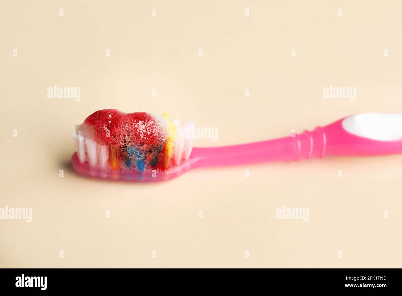 Toothbrush with paste and blood on beige background, closeup. Gum inflammation Stock Photo