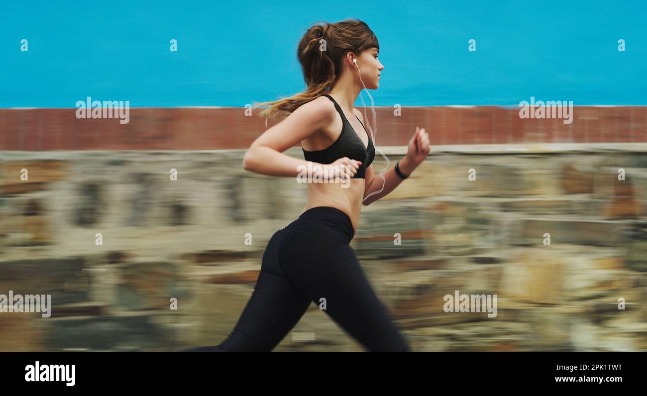 I didnt chose the running life, it chose me. an attractive young woman wearing gym wear and running down the street alone. Stock Photo