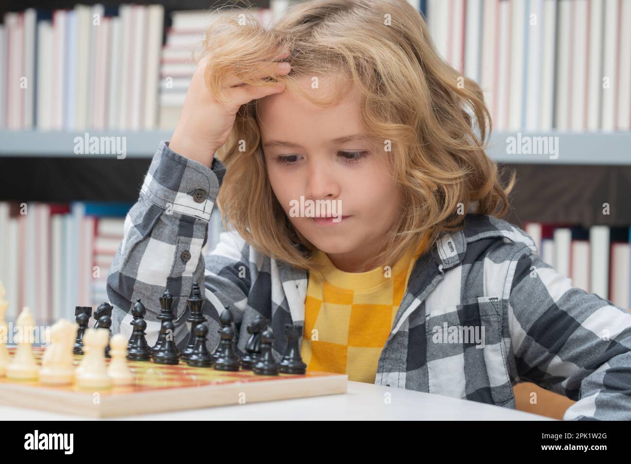 Chess school. Little kid play chess. Thinking child. Chess game for kids. Intelligent, smart and clever school boy. Stock Photo