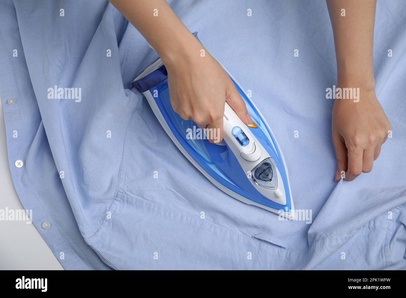 Woman ironing clean shirt on white table, top view Stock Photo