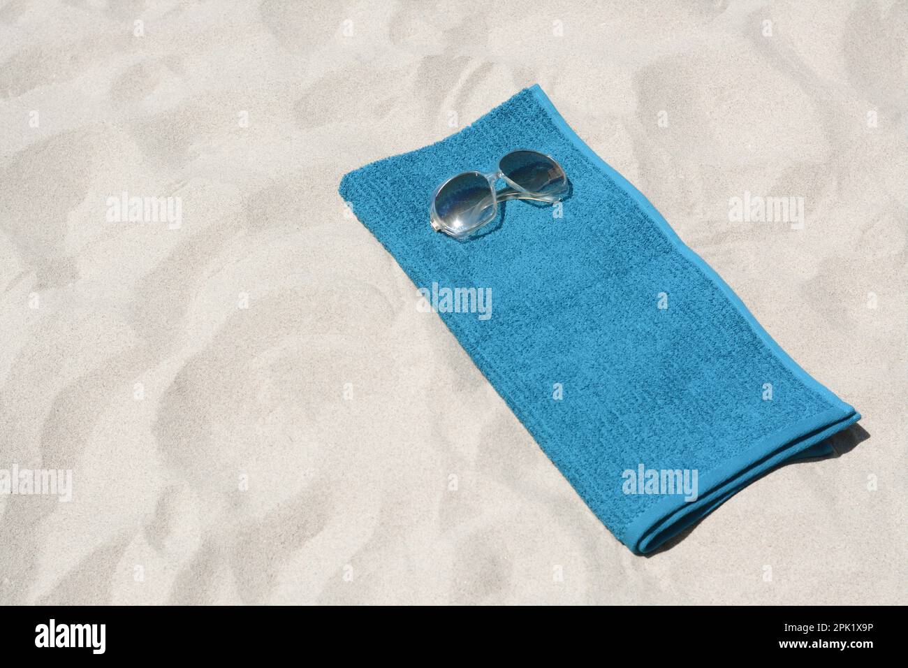 Soft blue towel and sunglasses on sandy beach, space for text Stock ...