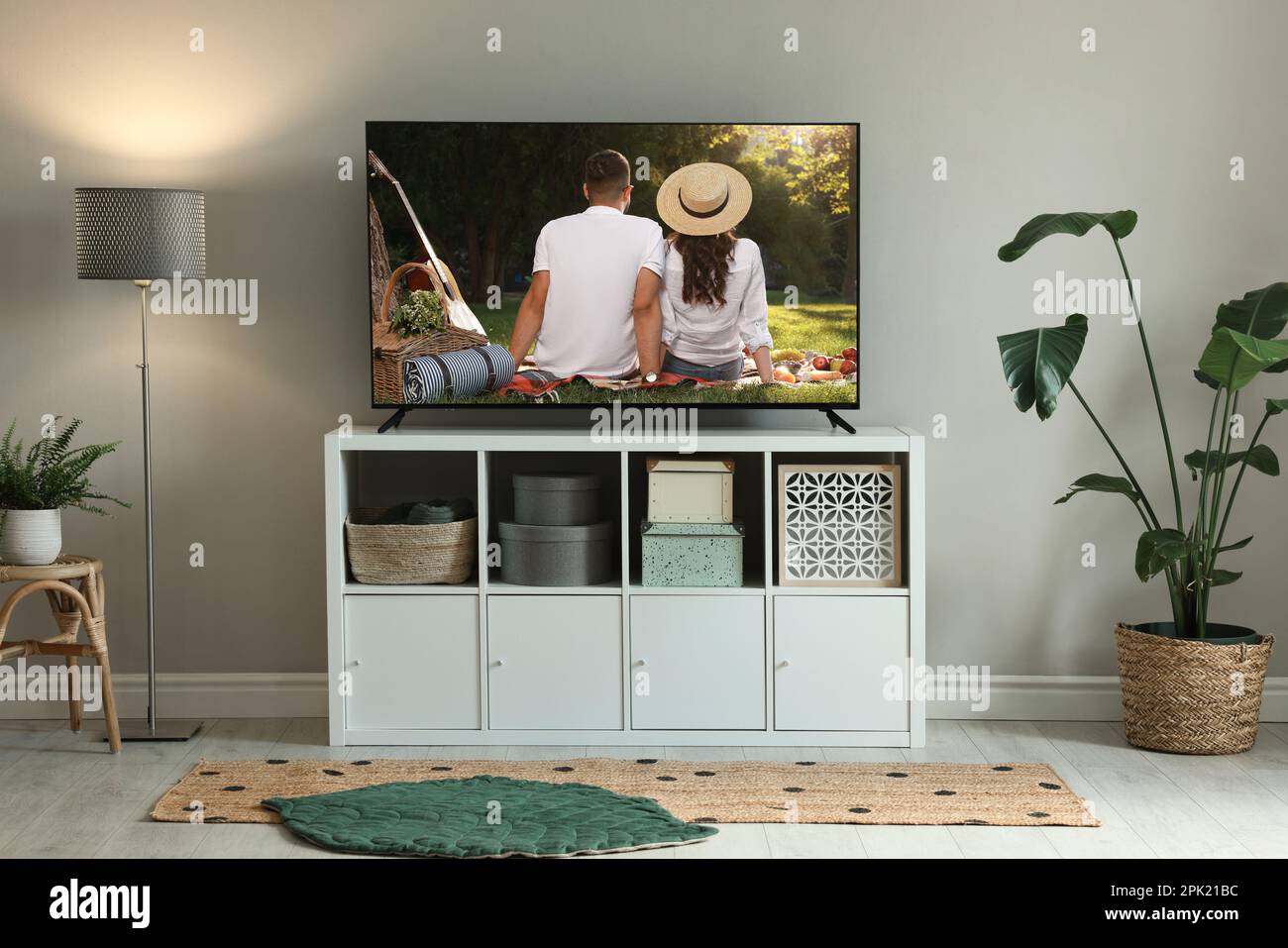Modern TV set on wooden stand in room. Scene of romantic movie on screen Stock Photo
