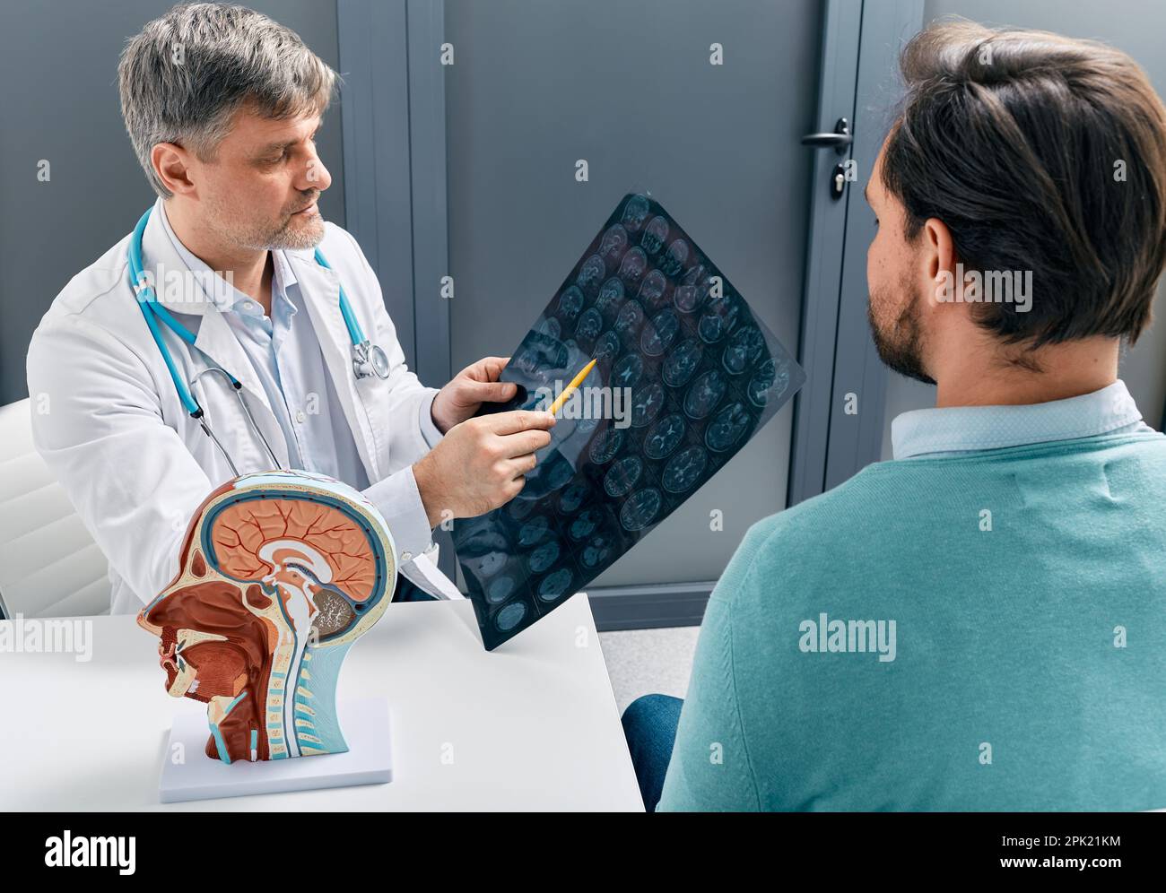 doctor explaining to male patient results of MRI scan of his brain. Diagnosis of diseases and head injuries Stock Photo