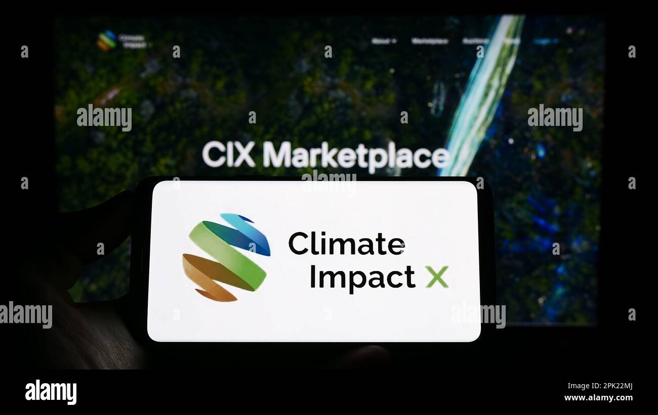 Person holding cellphone with logo of carbon exchange Climate Impact X (CIX) on screen in front of business webpage. Focus on phone display. Stock Photo