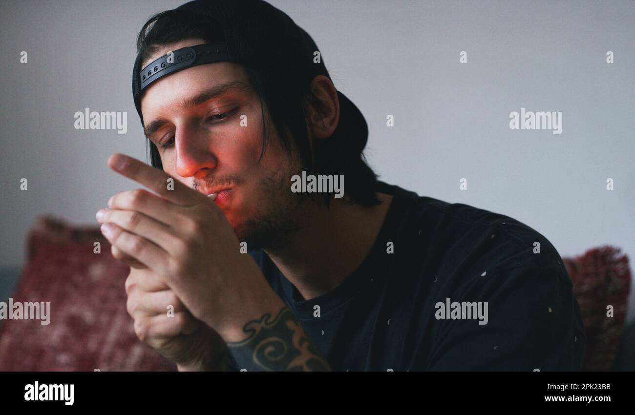 Sparking up a blunt. a young man smoking a marijuana joint at home ...