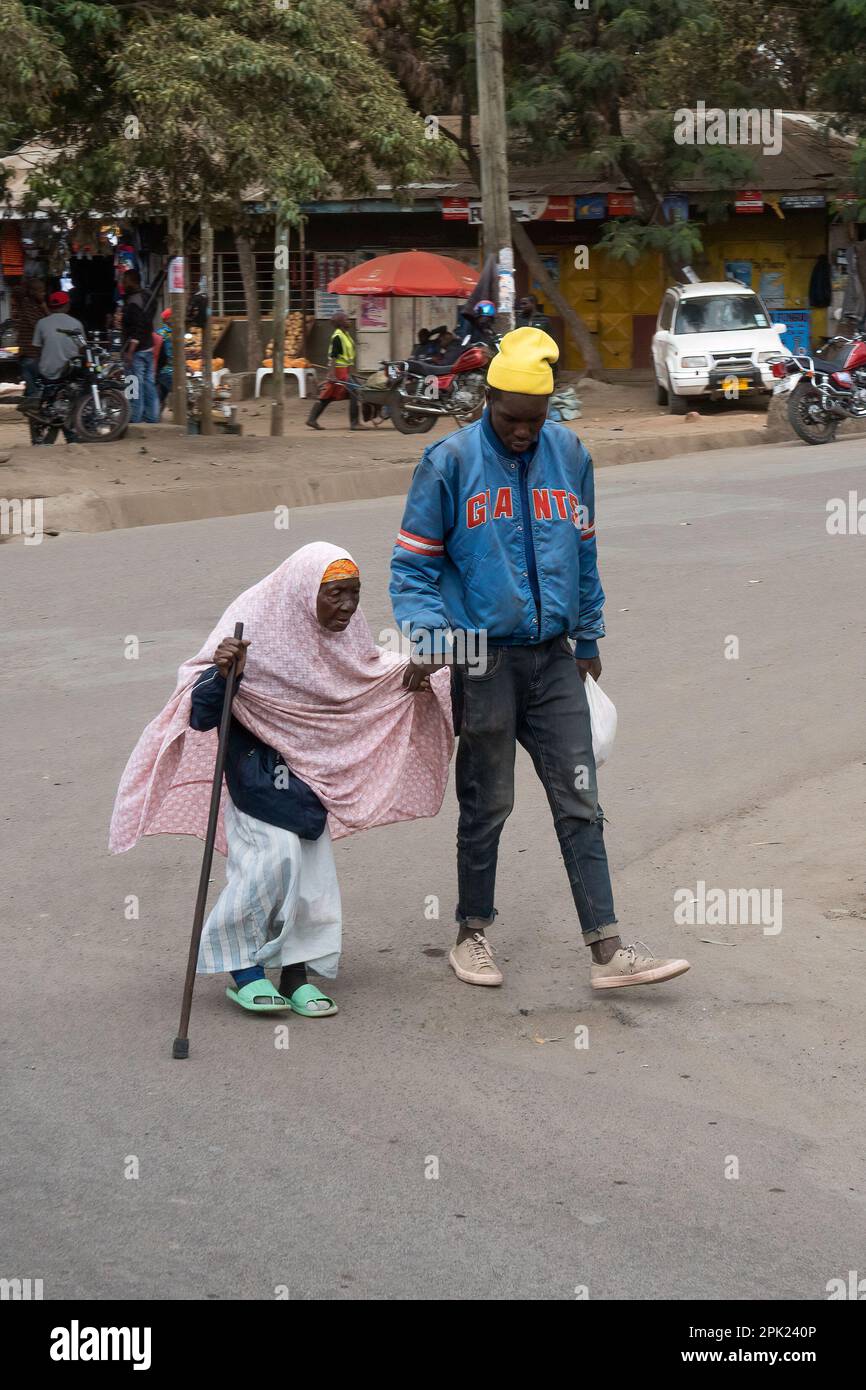 Arusha, Tanzania - October 17th, 2022: A man supporting an elderly woman in the main street of Arusha, Tanzania. Stock Photo