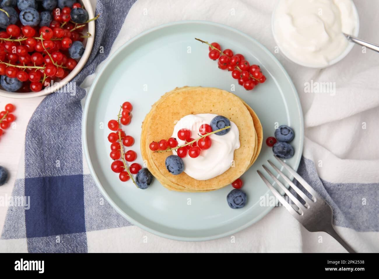 Tasty pancakes with natural yogurt, blueberries and red currants on table, flat lay Stock Photo
