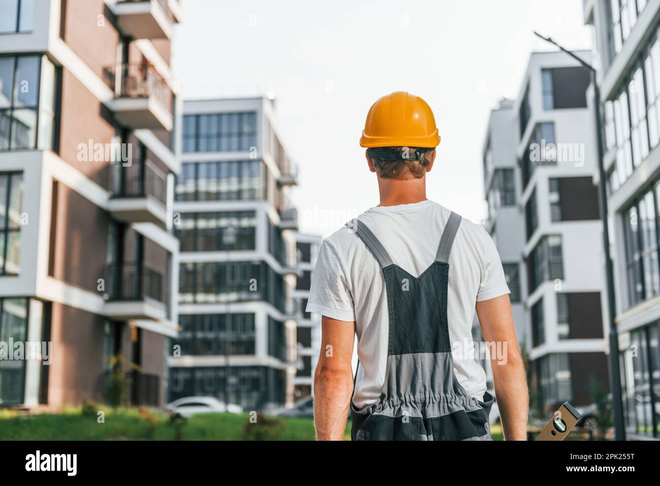 Rear view. Young man working in uniform at construction at daytime ...