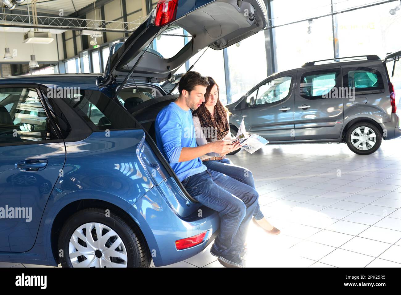 young couple in the showroom of a car dealership buying and testing vehicles Stock Photo
