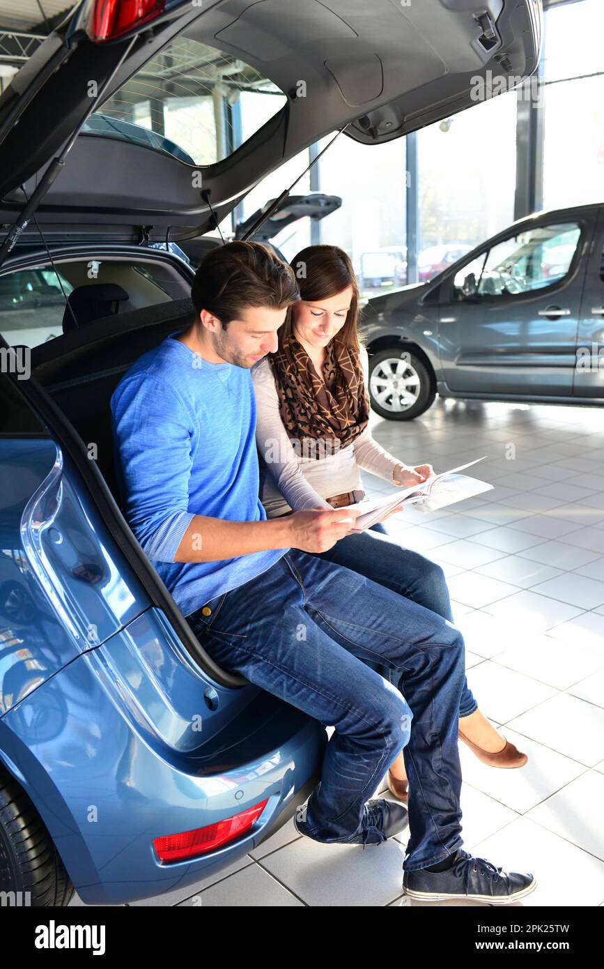 young couple in the showroom of a car dealership buying and testing vehicles Stock Photo