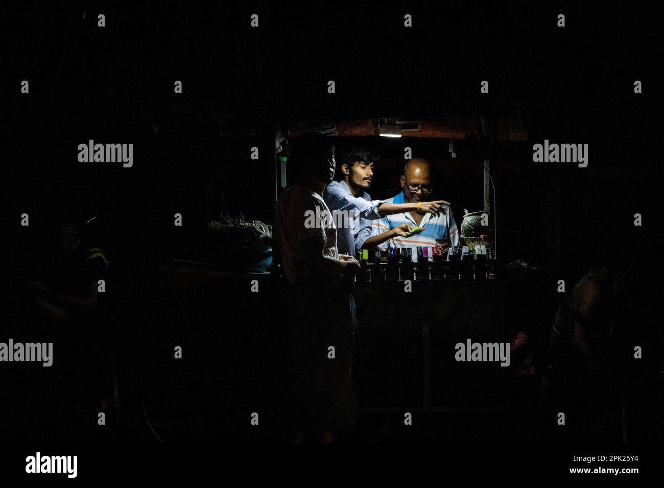 April 2, 2023, Yangon, Myanmar: Betel nut vendors prepare their product under a tiny lamp powered by a generator during a blackout on the street in Yangon. Due to soaring costs and the lack of hydropower during the dry season, the military junta (Tatmadaw) rations electricity throughout Yangon daily, leaving large sections of the city (townships) completely blacked out everyday. Daily life during the deadly civil war in Myanmar. On February 1, 2021, the military junta government (Tatmadaw) seized power by coup, jailing the democratically-elected government and plunging the country into an ongo Stock Photo