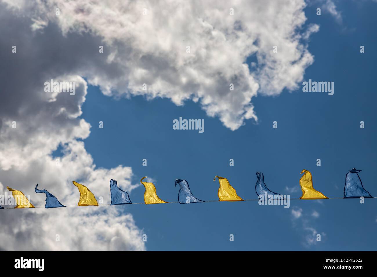 Yellow and blue triangular festival flags on sky background with white ...