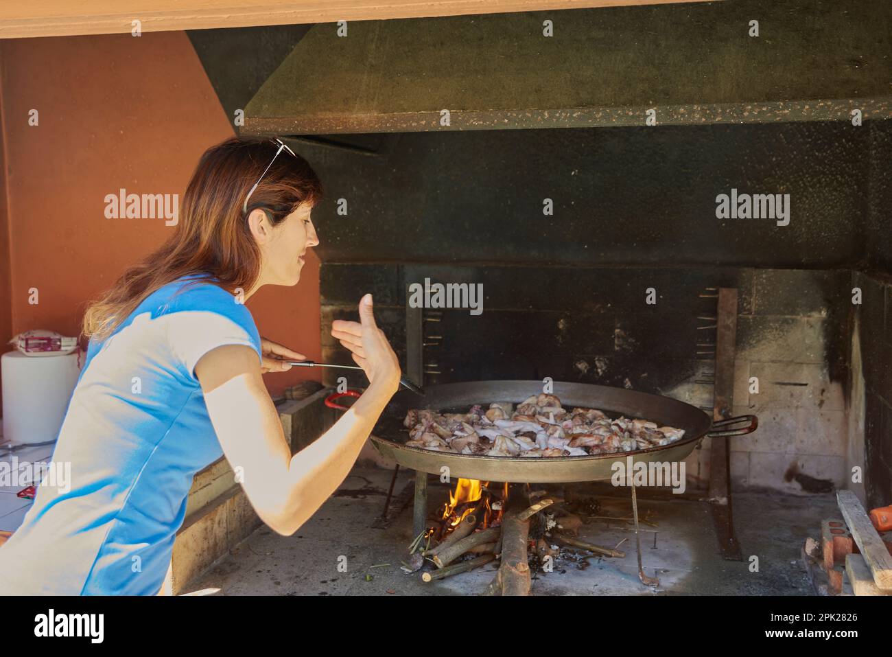 Girl Smelling And Cooking A Traditional Paella With Wood Fire Stock