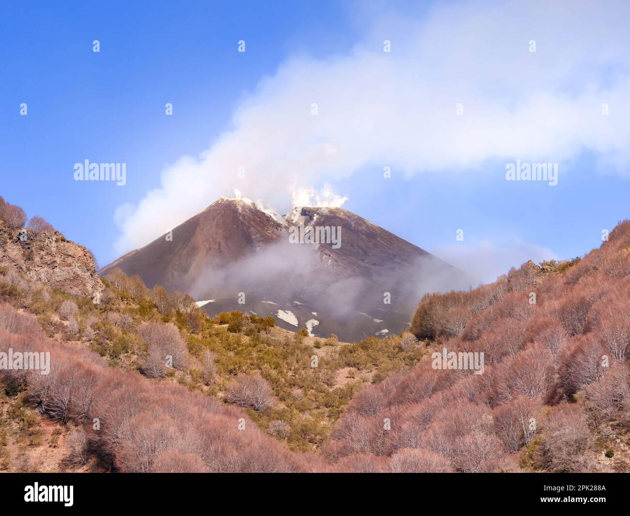 Cratere del vulcano Etna durante giornata di sole e cielo blu con emission di fumo - turismo e vacanze in Sicilia Stock Photo