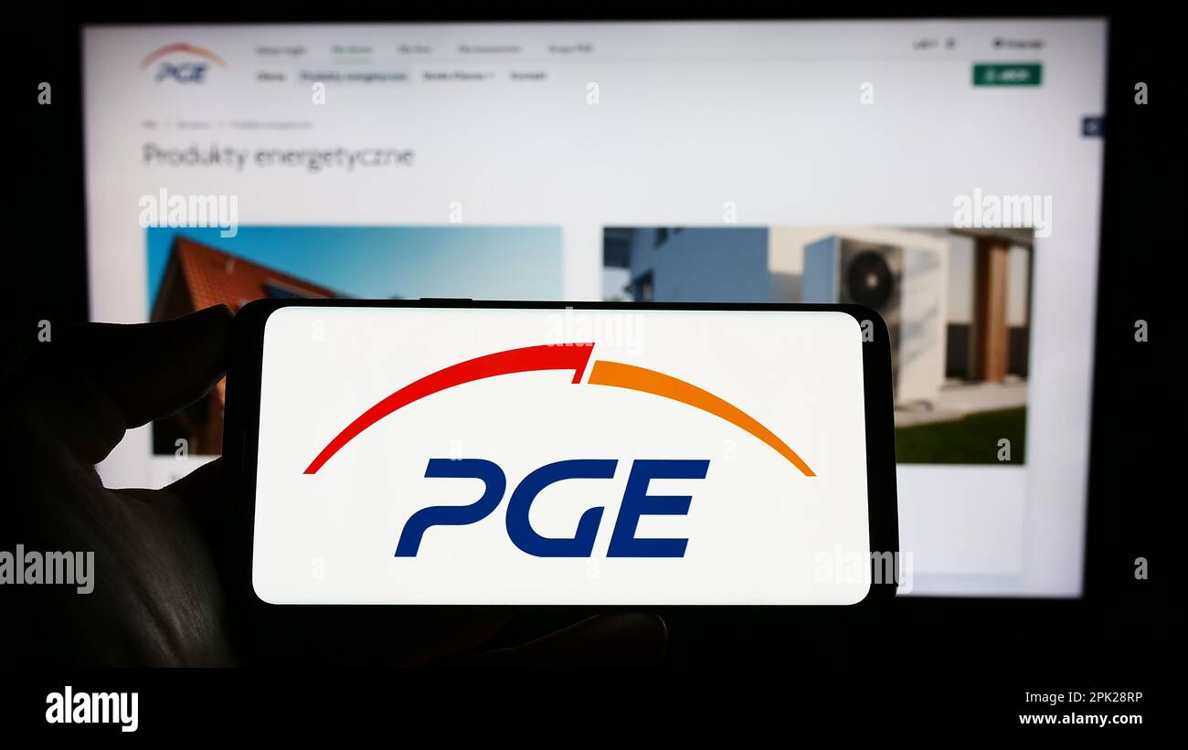 Person holding cellphone with logo of company PGE Polska Grupa Energetyczna SA on screen in front of business webpage. Focus on phone display. Stock Photo