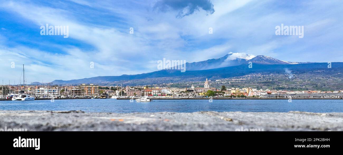 Panoramica del Porto di Riposto sul mare con  le case e la chiesa del paese con il vulcano Etna sullo sfondo - vacanze estive Stock Photo