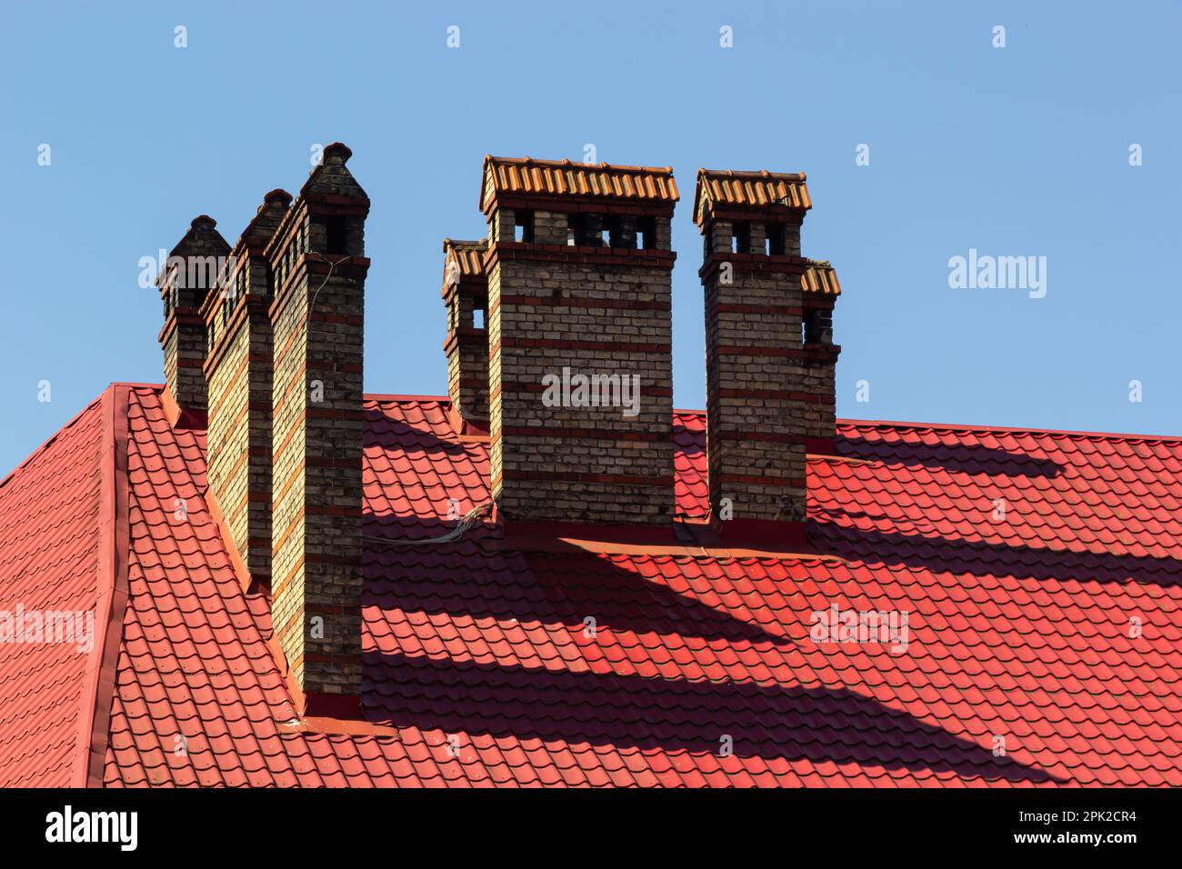 Red house roof with red brick chimney. Ceramic chimney, metal roof ...