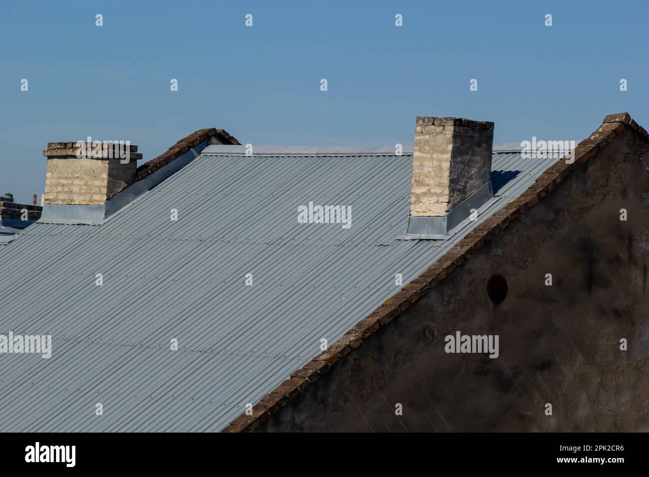 Roof of a new home. Ceramic chimney, metal roof tiles, gutters, roof window. Single family house. Stock Photo