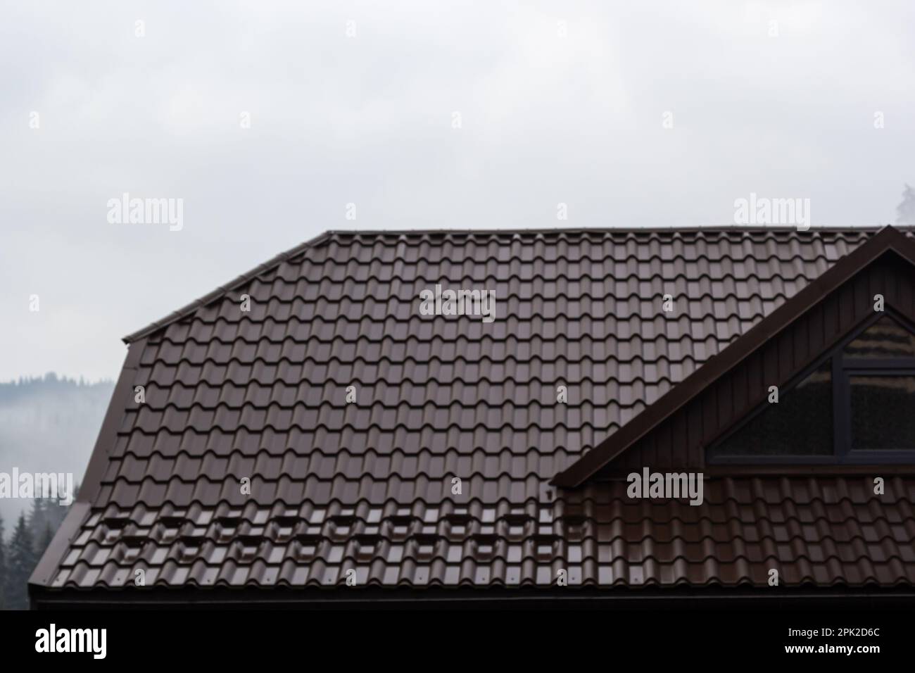 House with new brown metal tile roof and rain gutter. Metallic