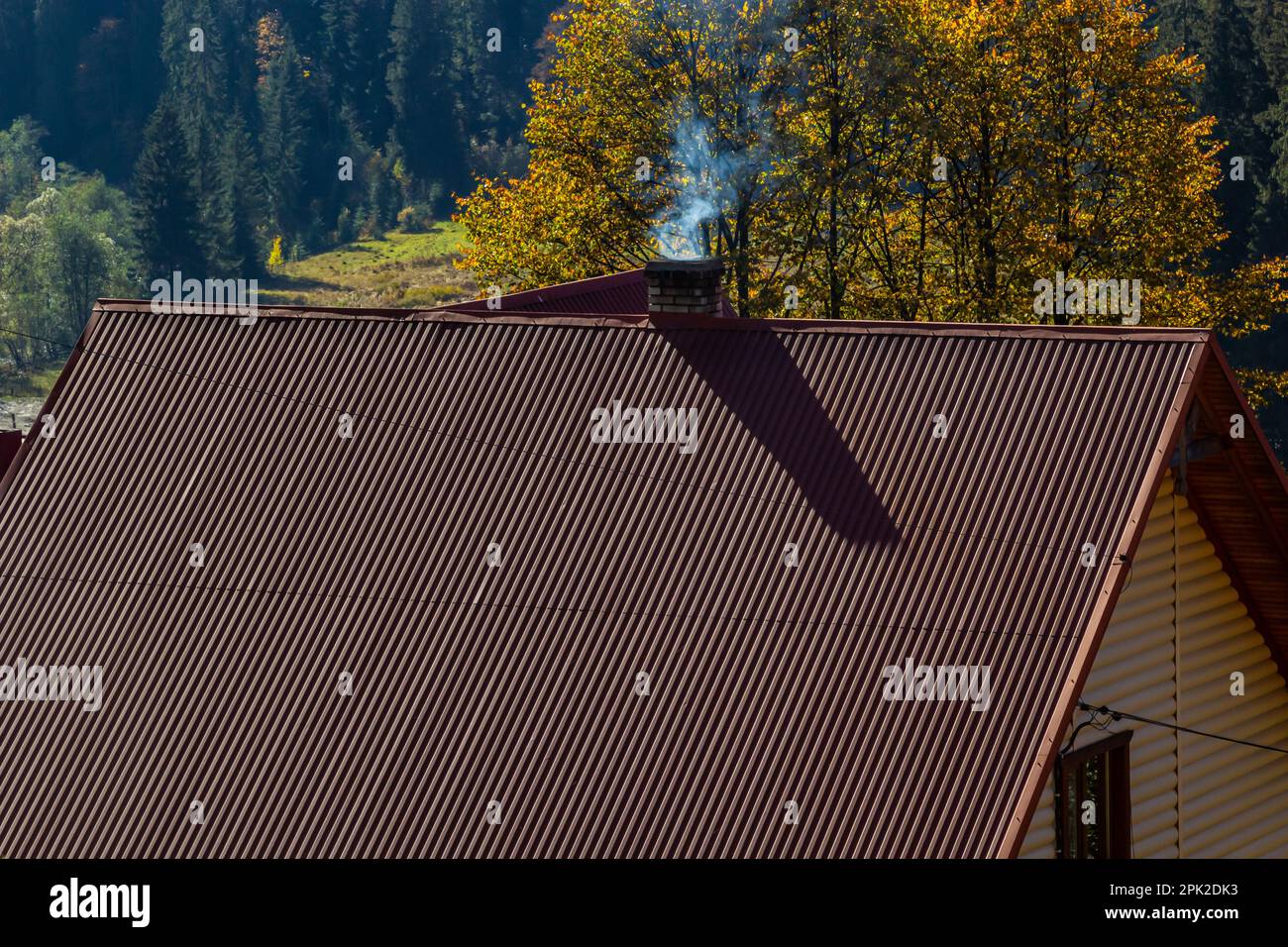 House with new brown metal tile roof and rain gutter. Metallic