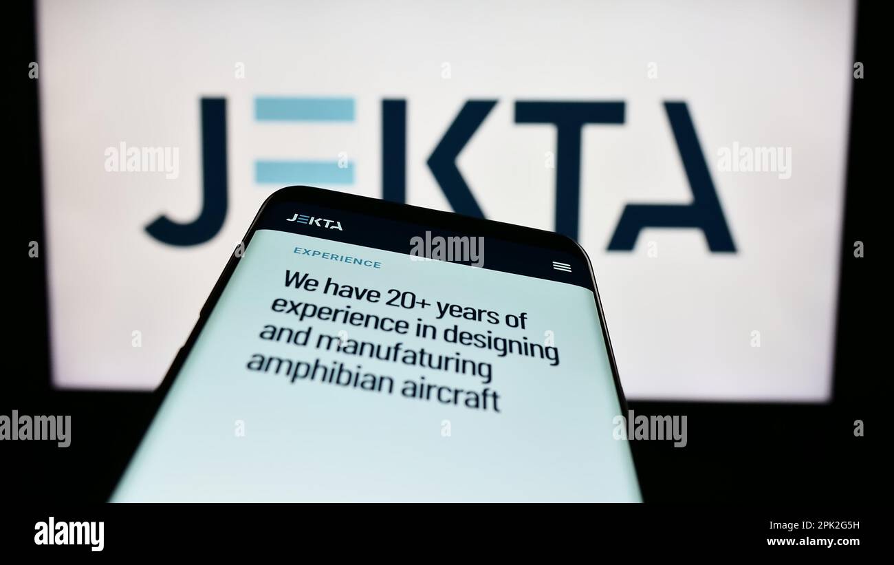 Smartphone with website of aviation company Jekta Switzerland S.A. on screen in front of business logo. Focus on top-left of phone display. Stock Photo