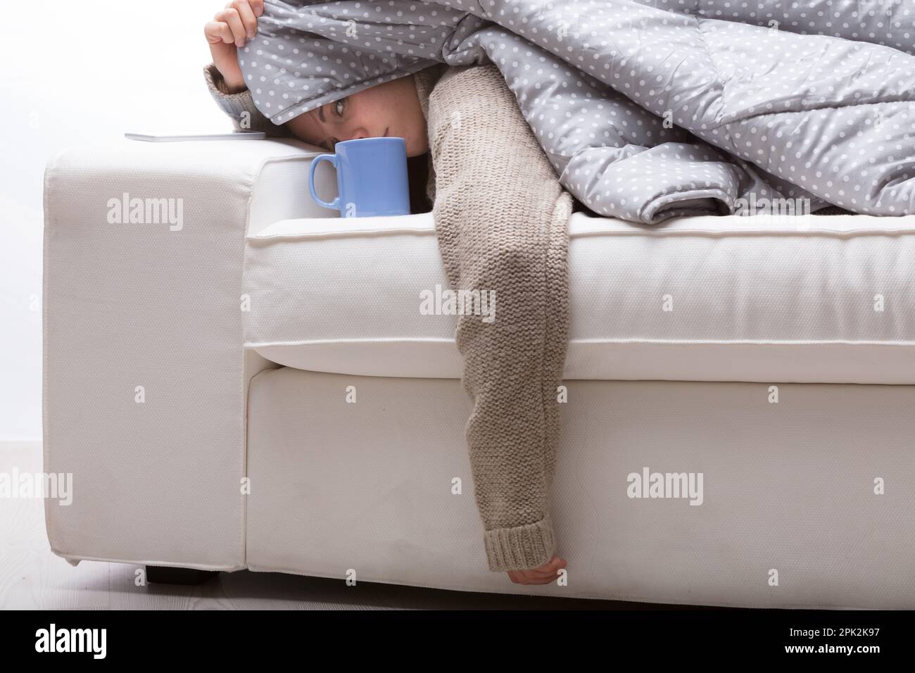 woman, lying on front, white couch, warm quilt, sweater, overwhelmed