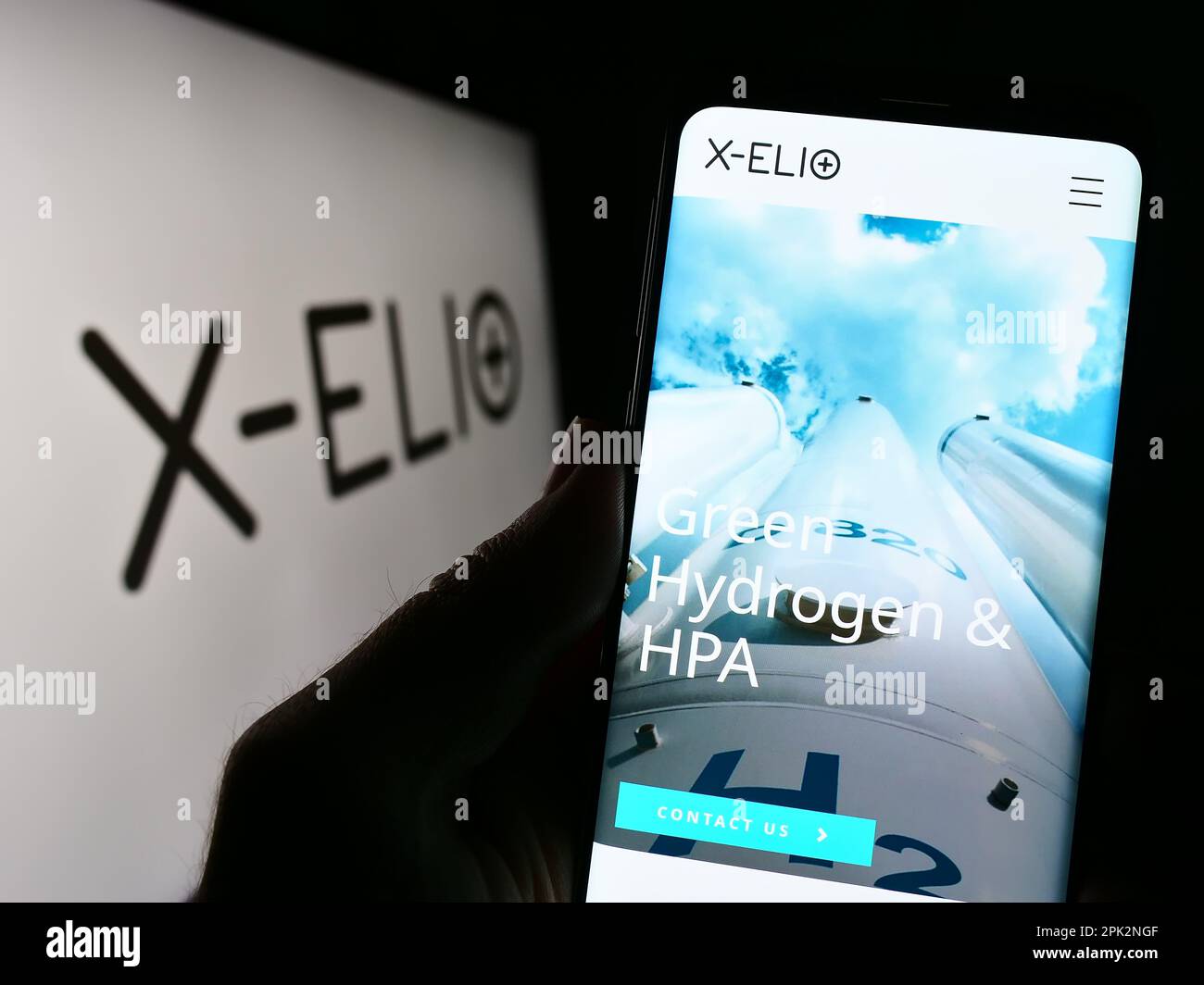 Person holding cellphone with webpage of Spanish renewables company X