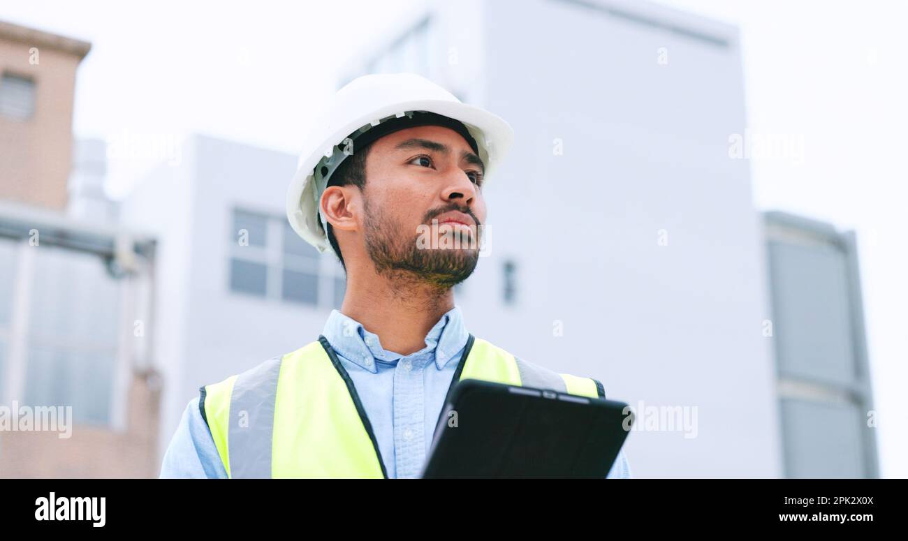 Construction worker holding a digital tablet while doing inspection. Organized male engineer or technician in a hardhat checking project plan with Stock Photo
