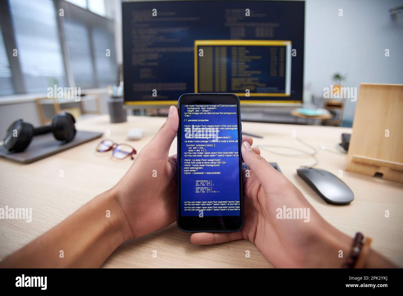 POV of male hands holding smartphone with code lines while programming mobile app, copy space Stock Photo