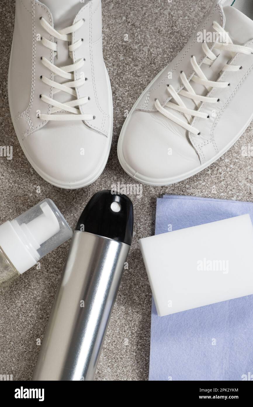 Applying a water-repellent hydrophobic spray to white women's sneakers.  Protection of shoes from moisture, dirt and unpleasant odor Stock Photo -  Alamy