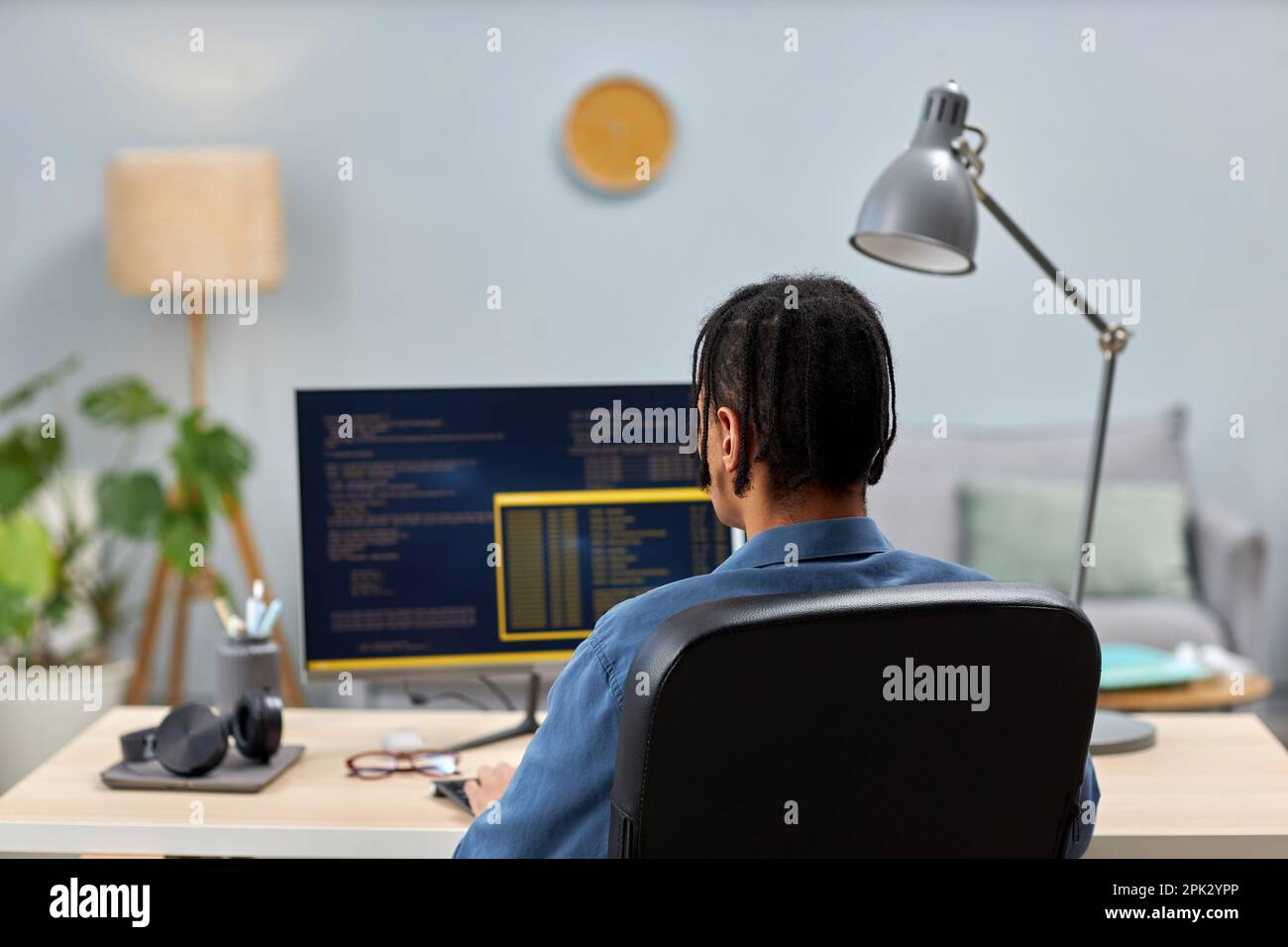 Back view of male IT professional writing code while working at office workplace, copy space Stock Photo