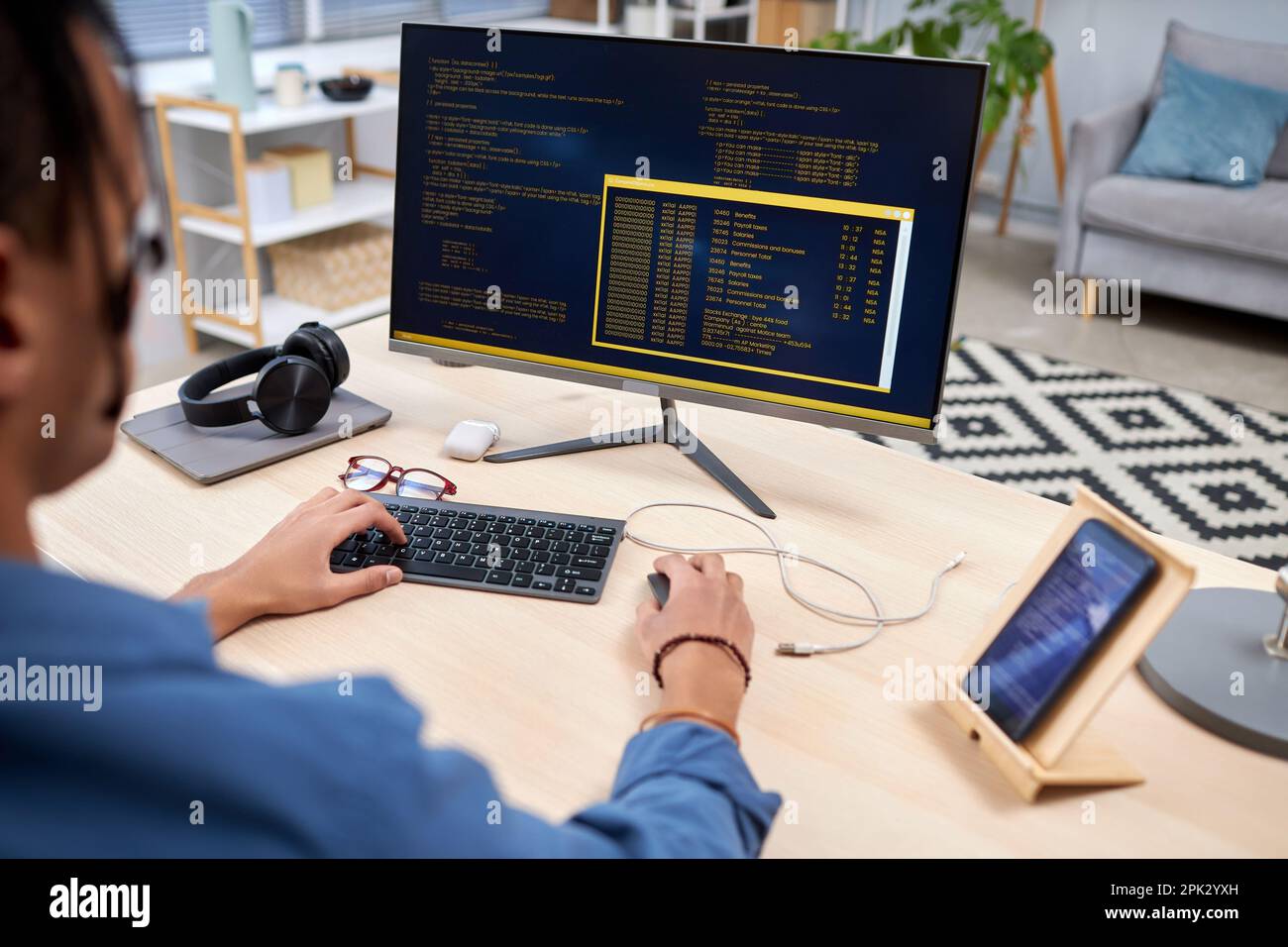 High angle view at young IT programmer writing code for mobile devices at home office workplace Stock Photo