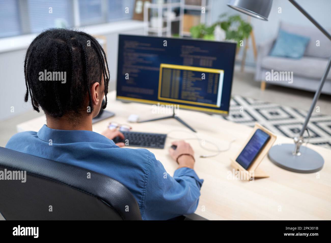 Back view at black young man writing code while studying computer programming at home, copy space Stock Photo