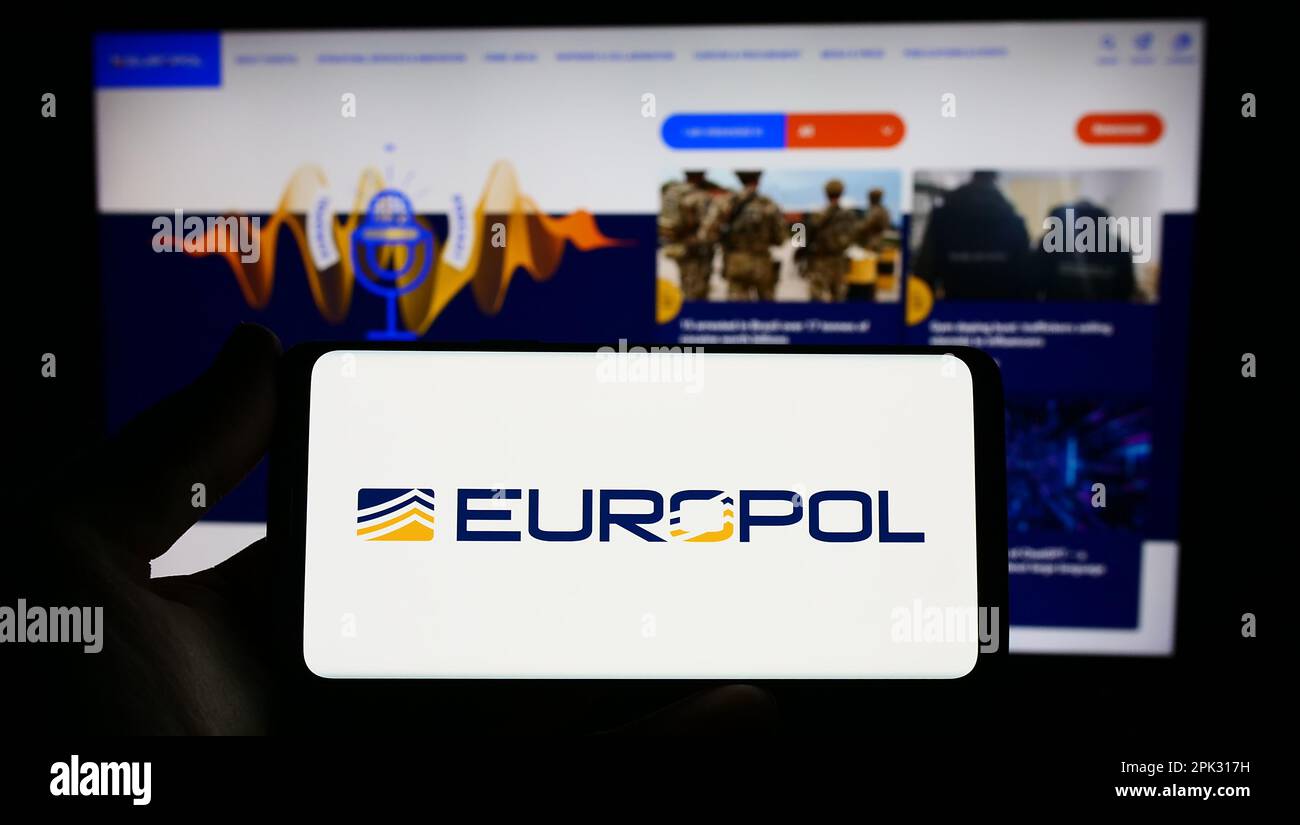 Person holding smartphone with logo of EU law enforcement agency Europol on screen in front of website. Focus on phone display. Stock Photo