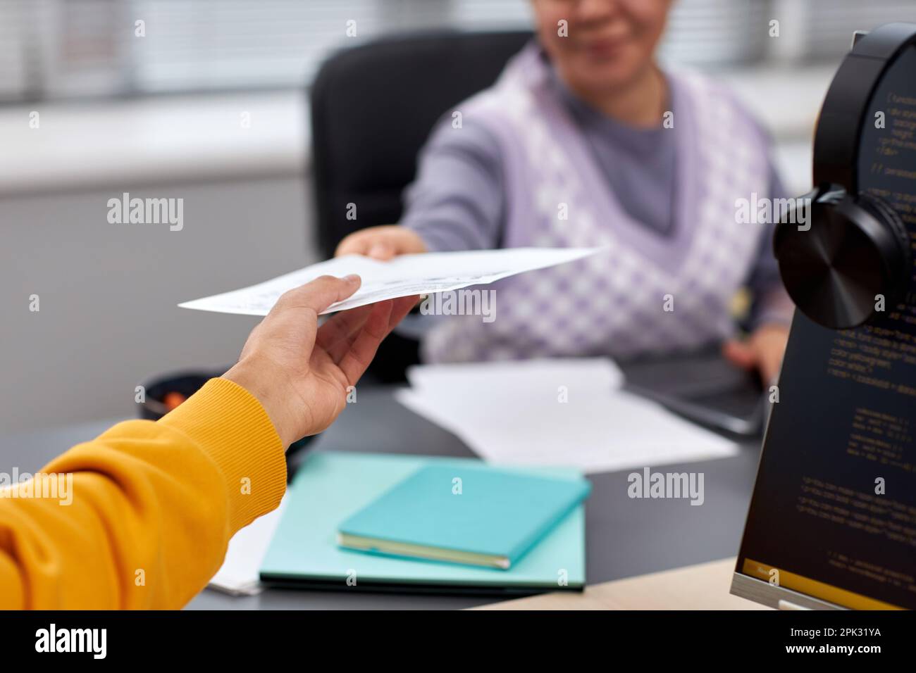 Close up of two young people handing document across table in office while collaboration on IT project, copy space Stock Photo