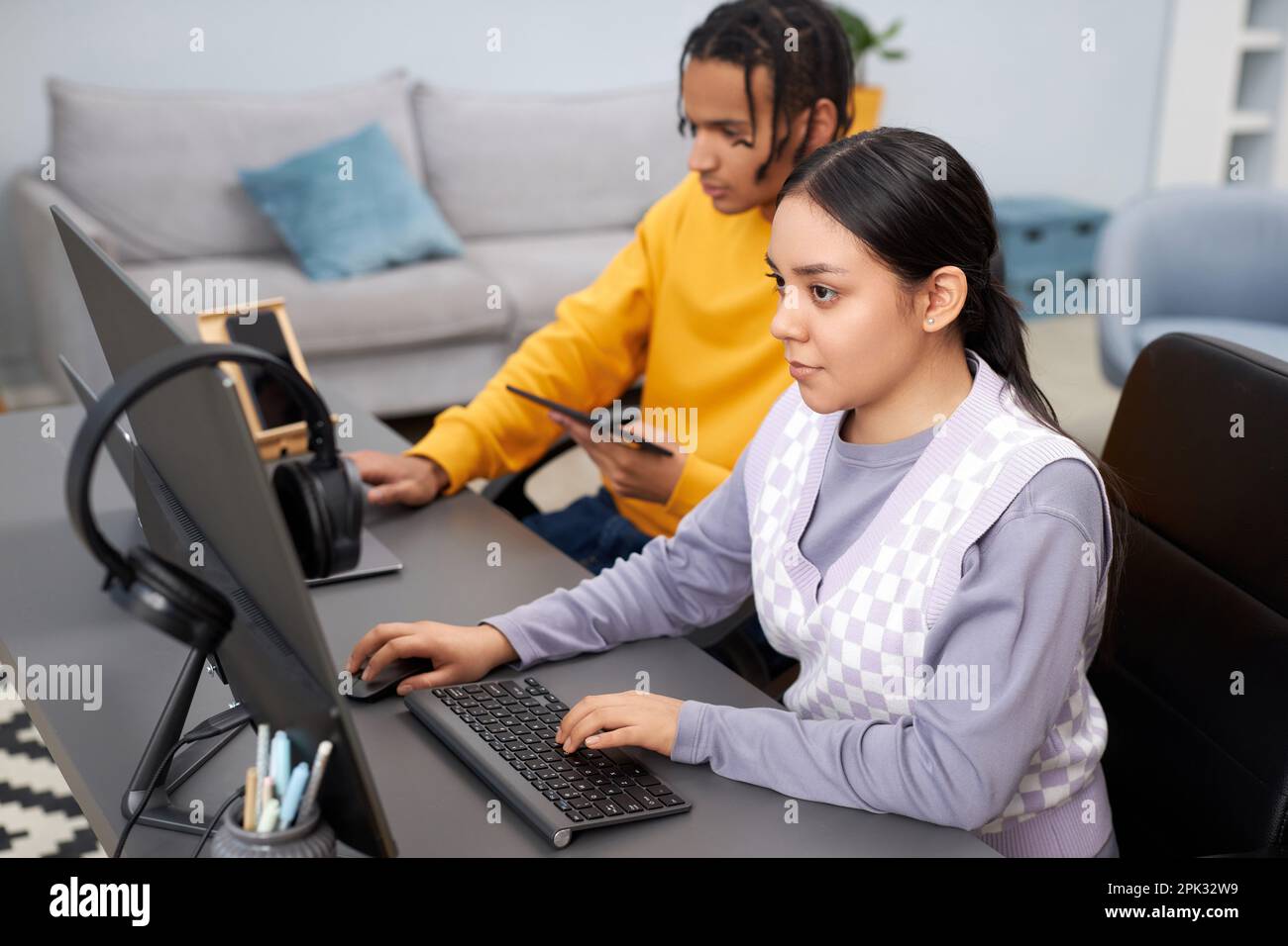 High angle view of two young people writing code in office with focus on multiethnic woman in foreground Stock Photo