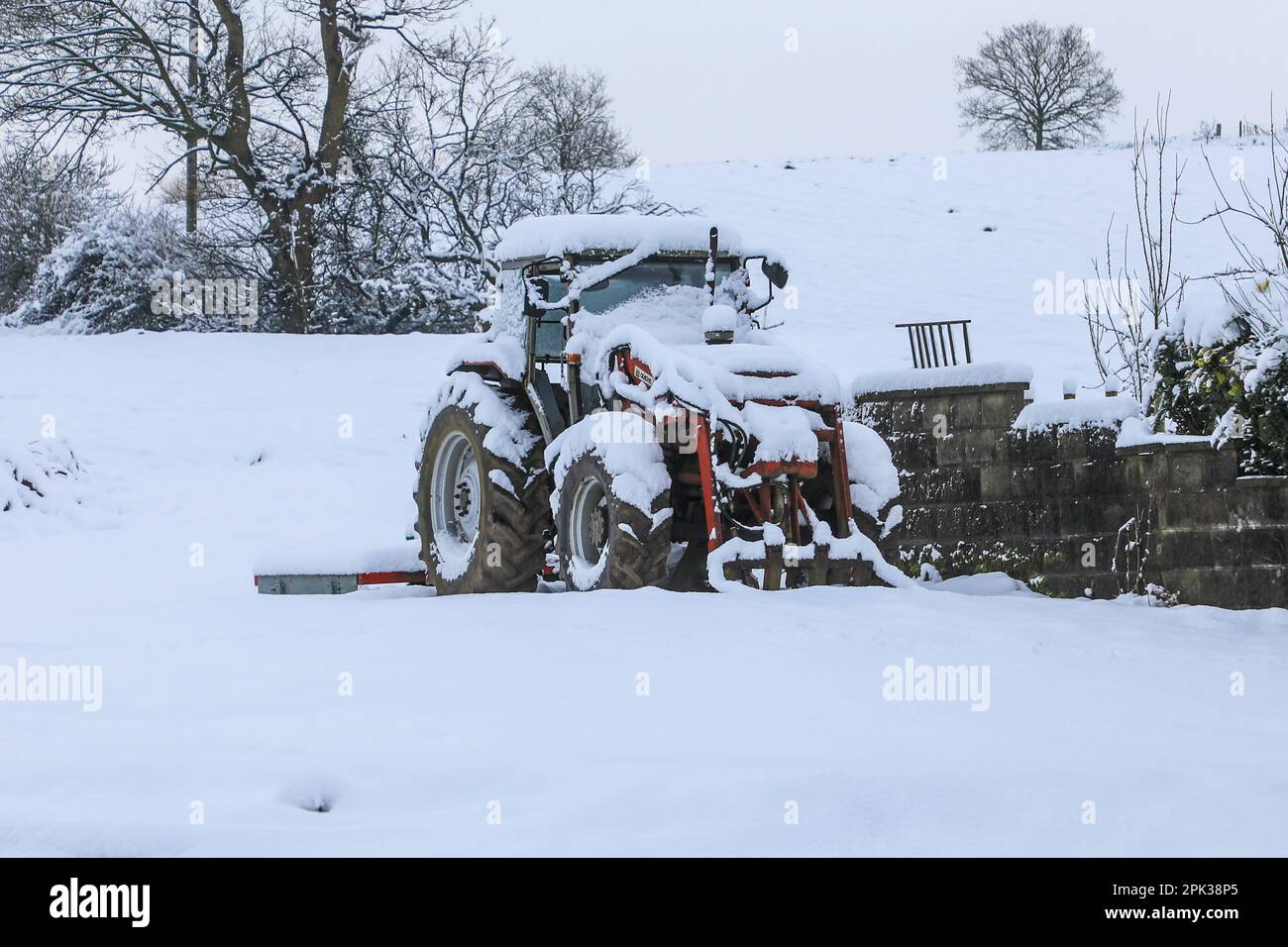 A tractor covered in snow on a winter snowy day, England, UK Stock Photo