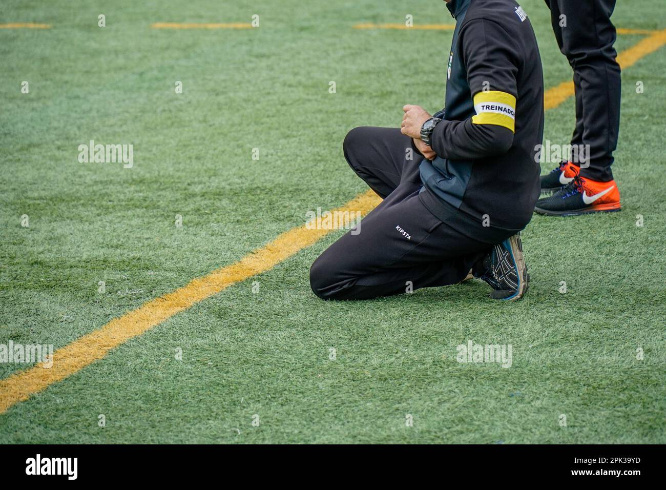 Évora, Portugal, February 19 and 20, 2023. Football coach on his knees giving instructions into the field. Stock Photo