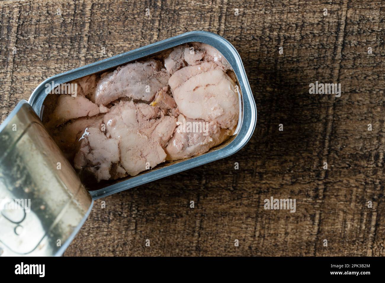 Open tin can with cod liver on wooden table background, close up, top ...