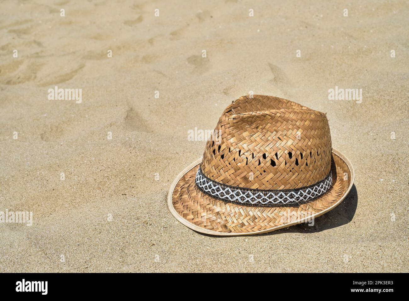 Men's straw beach hat on the sand at the beach, close-up, copy
