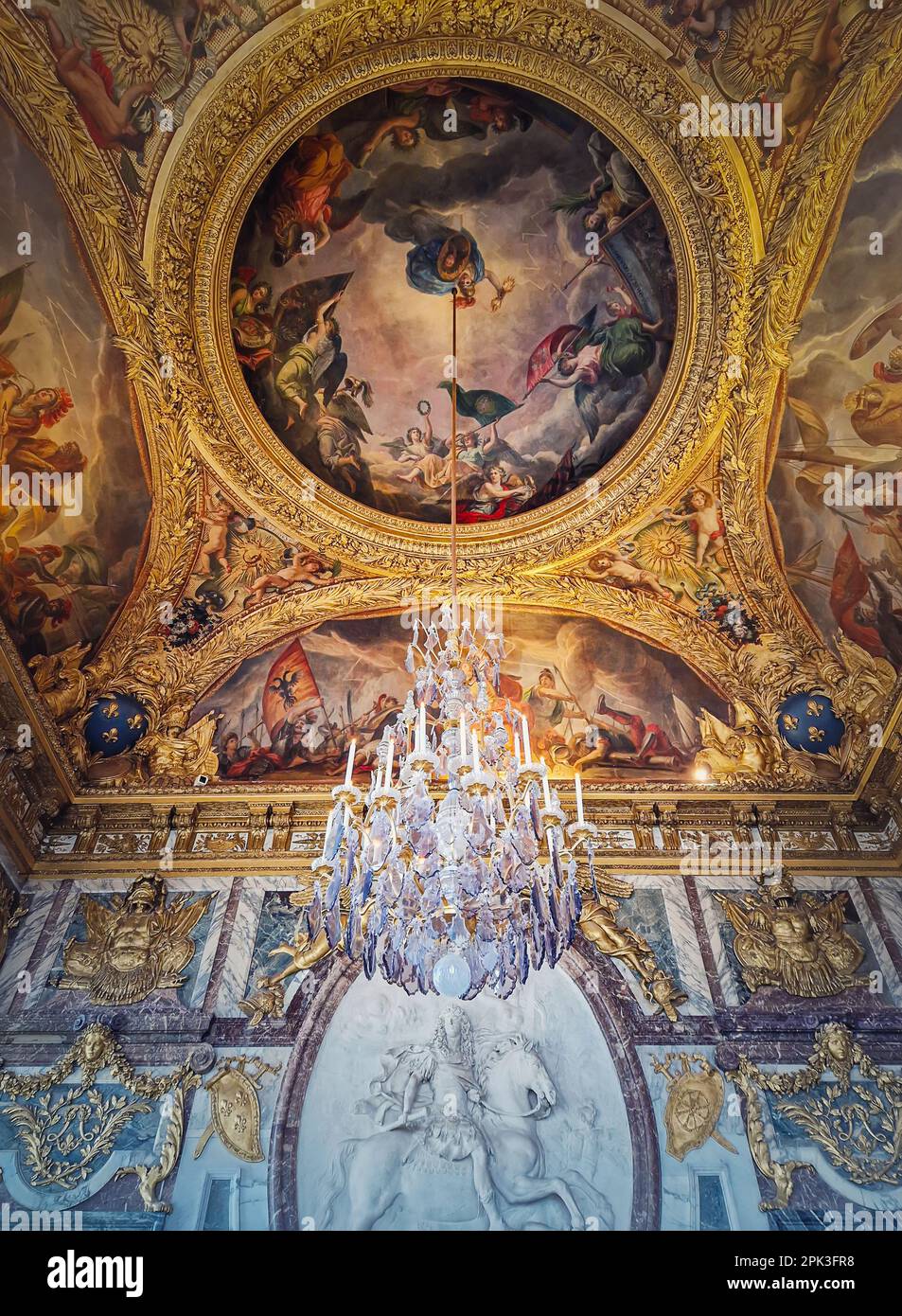 The War Room, Palace of Versailles, France. Chandelier hangs out of the golden painted ceiling above the stucco medallion of Louis XIV on horseback Stock Photo