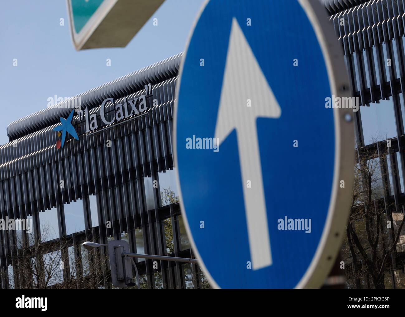 A traffic sign in front of the facade of the CaixaBank building on April 5,  2023, in Madrid, Spain. CaixaBank is a Spanish bank headquartered in  Madrid, founded in 2011 by Caja