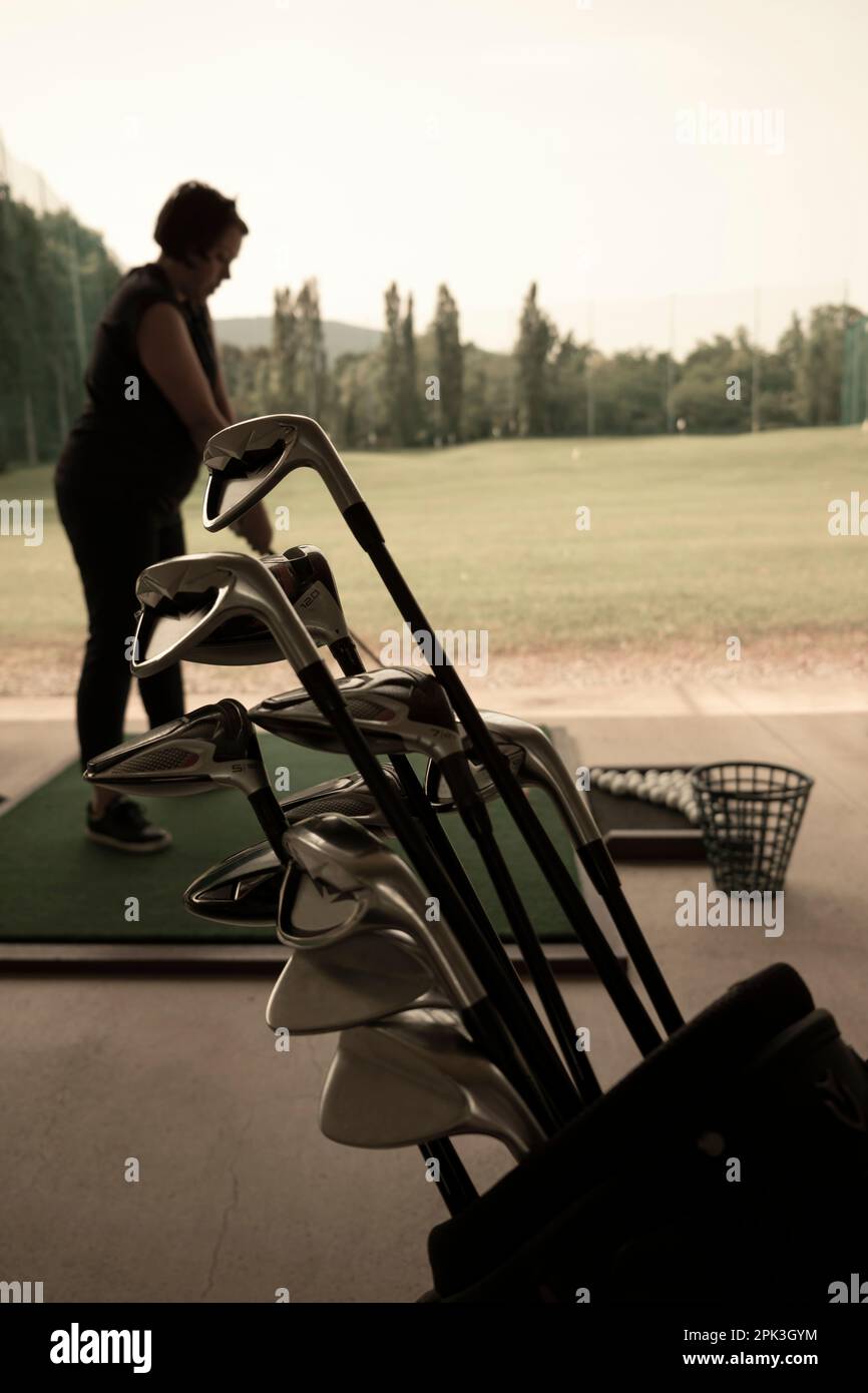Golfer Practice in Driving Range and a Golf Bag with Golf Clubs in