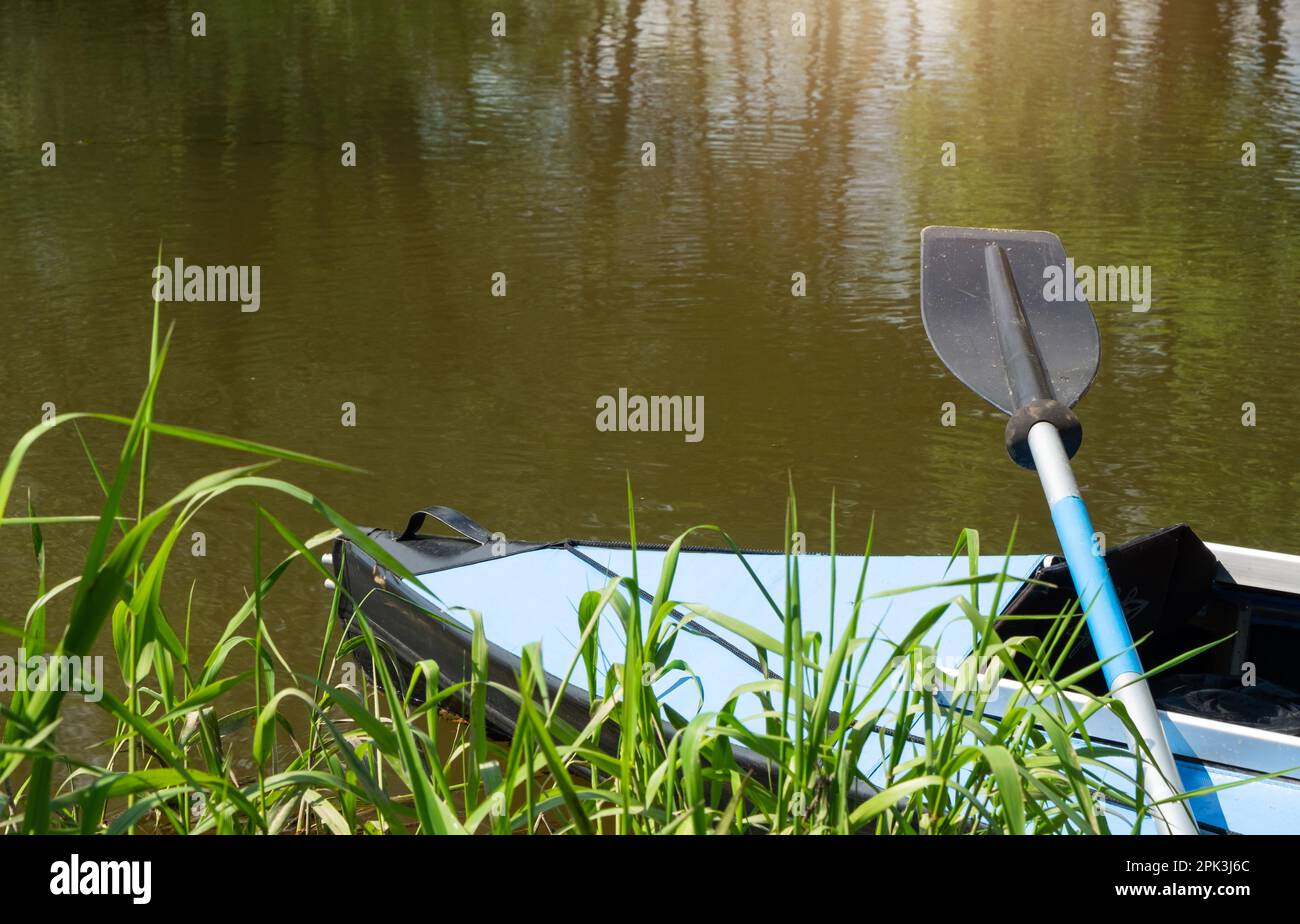 Tourist canoes with paddles stand on the river coast in summer on a