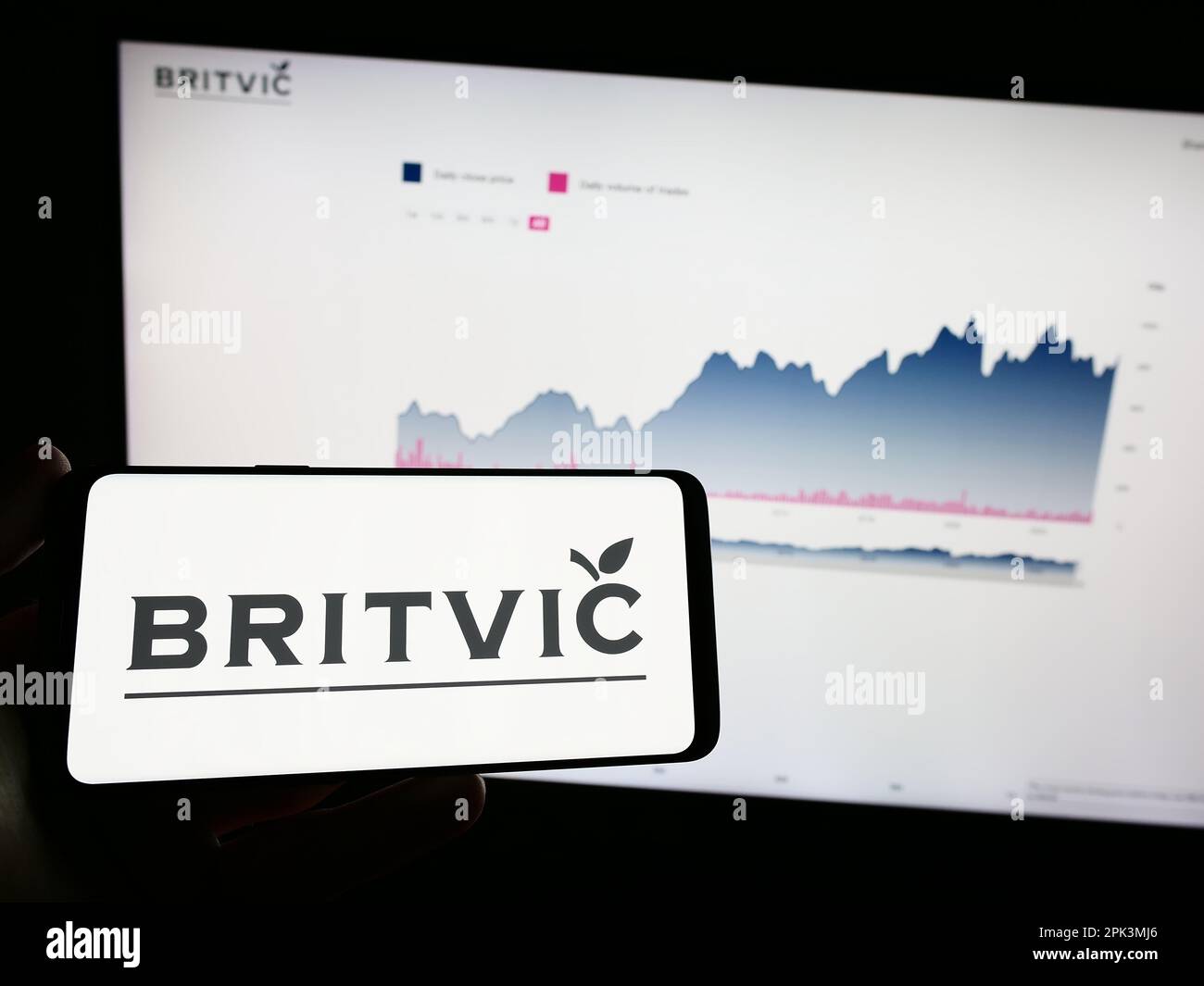 Person holding mobile phone with logo of British soft drinks company Britvic plc on screen in front of business web page. Focus on phone display. Stock Photo