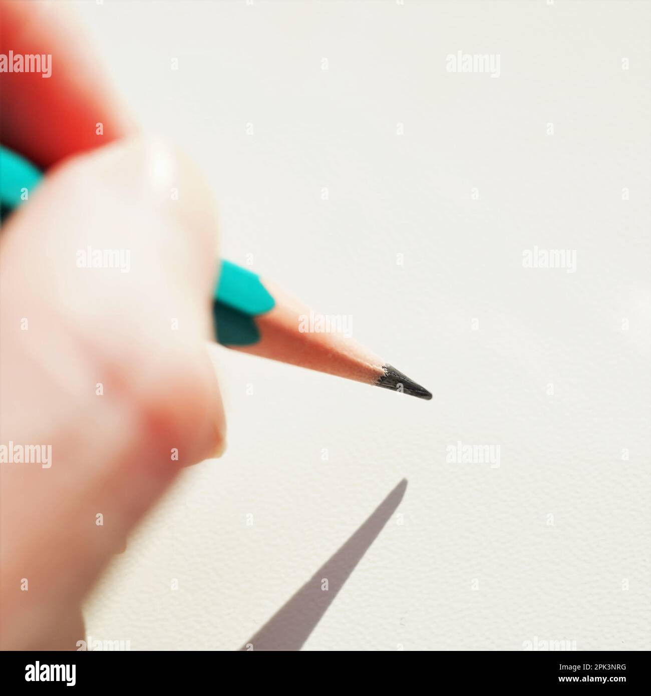 Green graphite pencil in female hand with sunlight. Stock Photo