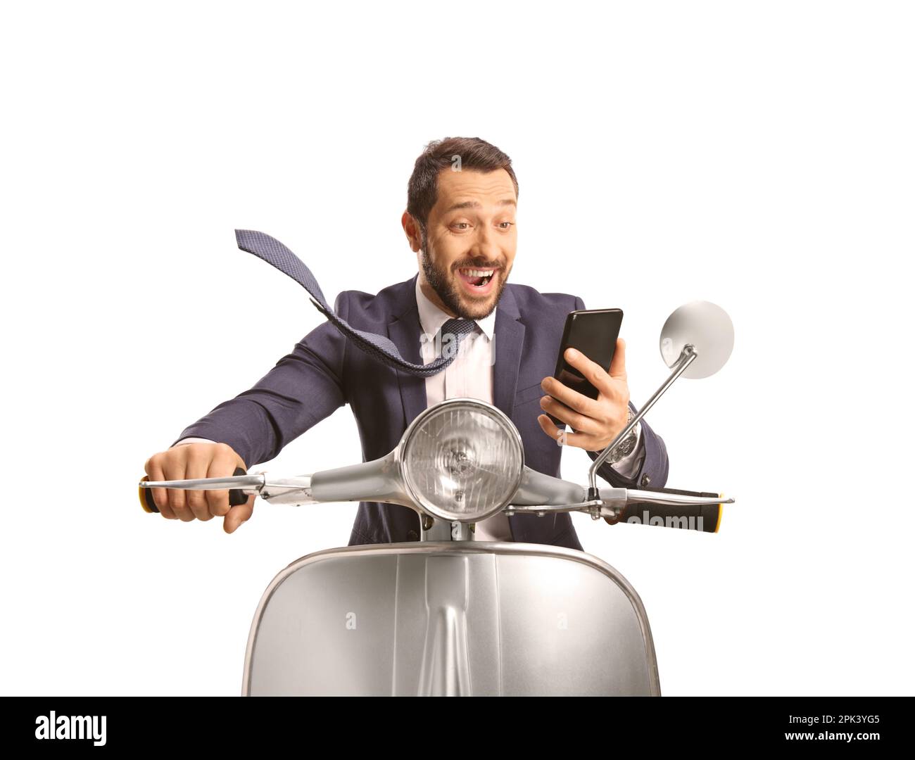 Excited young man riding a silver scooter and looking at a smartphone isolated on white background Stock Photo