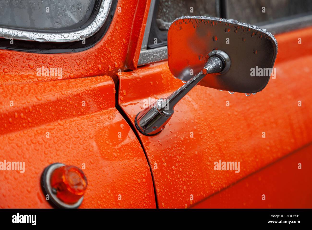 Rear view mirror of an orange retro car in the rain closeup Stock Photo