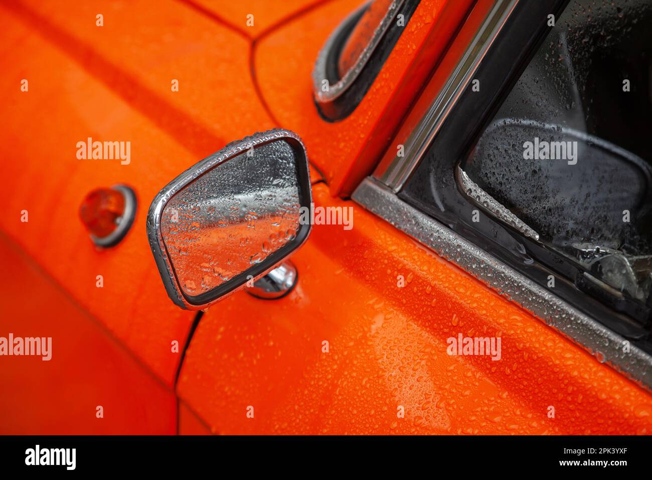 Rear view mirror of an orange retro car in the rain closeup Stock Photo